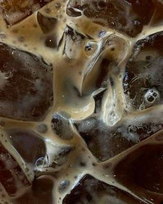 ice cubes with brown and white liquid on them in a bowl, top view