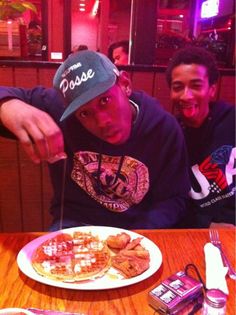 two men sitting at a table with plates of food