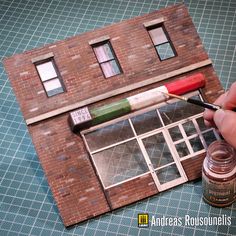 a person is painting the outside of a building with paintbrushes and an acrylic tube