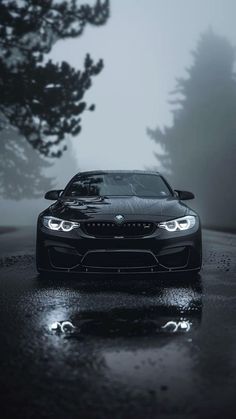 a black sports car parked on the side of a road in the dark with fog