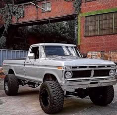 an old pickup truck parked in front of a brick building