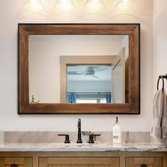 a bathroom vanity with a large mirror above it and lights on the wall behind it