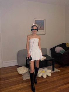 a woman in white dress and headphones standing on wooden floor next to couches