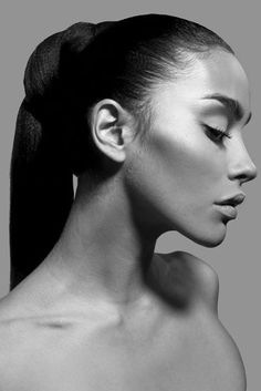 a black and white photo of a woman with her hair in a ponytail