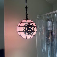 a pink light hanging from a ceiling in a room with plastic coverings on the walls