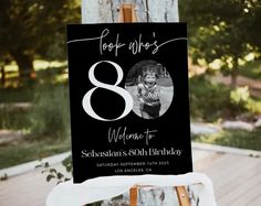 a black and white photo on a wooden easel for an 80th birthday party