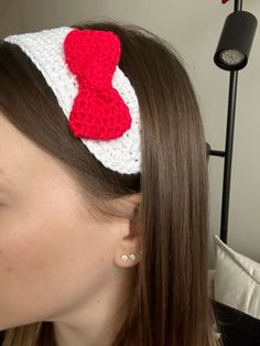 a woman wearing a red and white crocheted headband with a heart on it