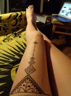 a woman's leg with a tattoo on it sitting in front of a laptop computer