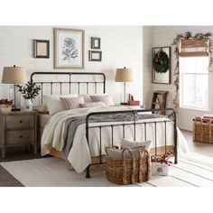 a bedroom with a metal bed frame and baskets on the floor, along with two lamps