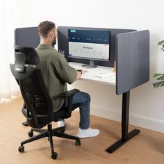 a man sitting in front of a computer desk with a monitor and keyboard on it