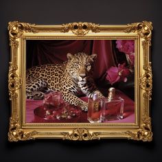 a framed photograph of a leopard sitting on a table next to a bottle of perfume