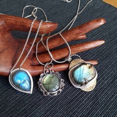 "Pendants of the collection ~NINFEA~ Stunning labradorite pieces, each of a different hue of colour ranging from deep blue to green and gold. The collection is inspired by water and by the beautiful plants and flower that grow into it, such as water lilies, \"nifea\" in Italian. All pieces are one of a kind and made with love. Here a full description of each piece: 1) Large piece of labradorite (3 x 2 cm) with green and golden hues set in a mix of silver and brass. The pendant is roughly 4.5 cm long and 3.5. cm wide. The back of the pendant features sun and cloud shaped cuts, thus showing the beauty of the stone from the back too. If desired, the pendant can be complemented by one of the two available types of chain. 2) Sleek pendant with a deep blue, tear-shaped labradorite piece. The pen Bohemian Hand Forged Sterling Silver Jewelry, Silver Labradorite Oval Pendant Jewelry, Nature-inspired Sterling Silver Wire Wrapped Necklaces, Handmade Silver Labradorite Jewelry, Spiritual Labradorite Oval Pendant Jewelry, Nature-inspired Wire Wrapped Sterling Silver Necklaces, Silver Wire Wrapped Necklaces, Nature-inspired Sterling Silver Wire Wrapped Jewelry, Silver Wire Wrapped Teardrop Pendant Jewelry