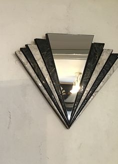 a triangle shaped mirror mounted to the side of a wall next to a white wall