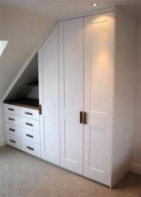 an attic bedroom with white cabinets and drawers