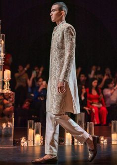 Exude regal opulence in this beige gold sherwani set that is fabricated using rich tussar fabric. The set has a sherwani, a kurta and pants. Ornated with all-over intricate hand work this ensemble is an epitome of exemplary craftsmanship. The full-sleeve open sherwani is stylishly stitched with a button front closure. Designed with a shirt collar, it is enhanced with cutwork detailing. Effortless and charming, this luxe addition exhibits a suave look dry-clean only if required. Slight variation in color is possible due to digital photography. Open Sherwani, Gold Sherwani, Kurta And Pants, Embroidered Sherwani, Gold Hand, Gold Hands, Hand Work, Cut Work, Shirt Collar