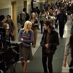 a group of people walking down a hallway next to each other with cameras around them