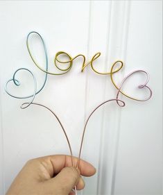 a person is holding some wire with the word love spelled on it in different colors