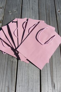 four pieces of pink paper sitting on top of a wooden table