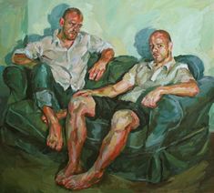 two men are sitting on a green couch