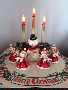 a group of christmas figurines sitting on top of a table next to candles