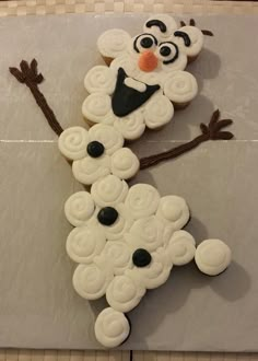 a cake shaped like a snowman sitting on top of a white tablecloth covered in icing