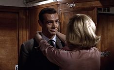 a man in a suit and tie standing next to a woman who is looking at him