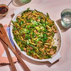 a bowl filled with noodles and vegetables next to chopsticks on top of a table