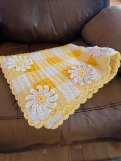 a crocheted blanket sitting on top of a brown couch