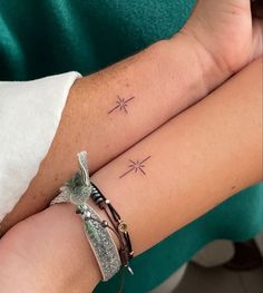 two people with matching tattoos on their arms, one is holding the other's arm