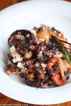 a white plate topped with octopus and vegetables