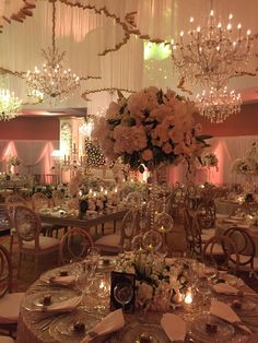 an elegant wedding reception set up with chandeliers and floral centerpieces