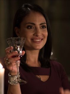 a woman holding a wine glass in front of a candle