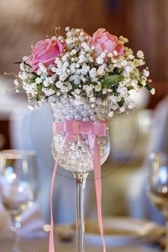 a vase filled with pink roses and baby's breath sitting on top of a table