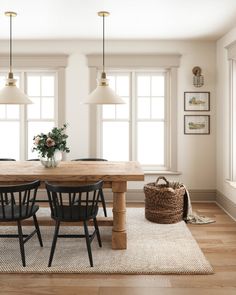 a dining room table with four chairs and a basket on the floor next to it