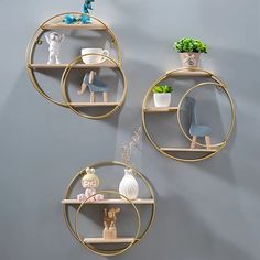 three circular shelves with plants and figurines on them against a gray wall,