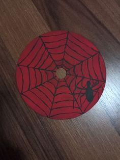 a wooden table with a red spider web on it and a black cat sitting in the center