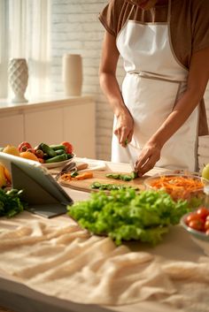 a woman in an apron cutting vegetables on a table