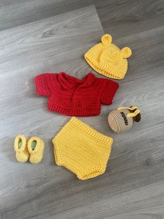 a crocheted baby outfit, booties and hat are laying on the floor