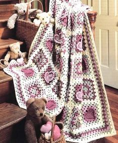 a teddy bear sitting on the stairs next to a crocheted blanket