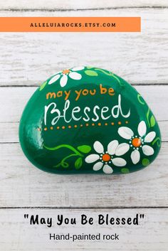 a green painted rock with the words may you be released on it and an image of daisies