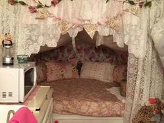 a bed with white curtains and pink bedspread in a room filled with stuffed animals