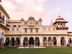 an ornate building with columns and arches on the front, surrounded by lush green grass