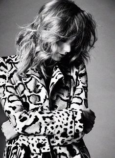 black and white photograph of a woman with her hair blowing in the wind wearing a leopard print coat