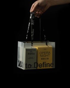 a person holding an open shopping bag with the words opera night written on it in chinese