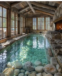 an indoor swimming pool with rocks in the water and large windows on either side of it