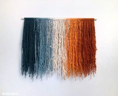 three different colors of yarn hanging on a wall