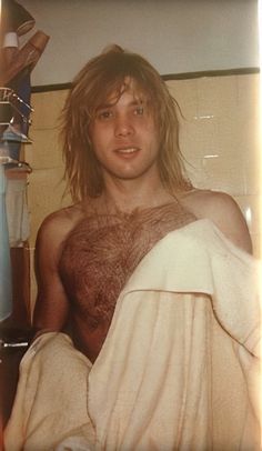 a man with long hair and no shirt in bed