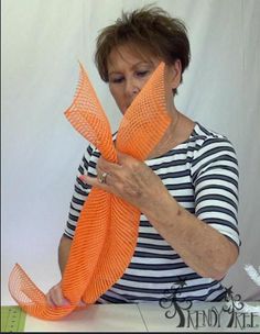 an older woman is working on something with orange yarn