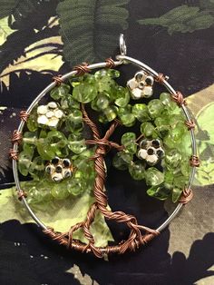 The tree of life represents the afterlife, and connection between the earth and heaven. The bond and affection to trees is so deep that Celts believed the actual trees were their ancestors, gatekeepers to the Celtic Otherworld. As such, the tree of life in Celtic Culture is sacred. This pendant is made of copper wire beaded with peridot chips and little silver flowers and wrapped on a silver hoop. Celtic Otherworld, Unique Tree Of Life Round Jewelry, Healing Tree Of Life Round Jewelry, Green Tree Of Life Jewelry Gift, Tree Of Life Pendant For Jewelry Making, Adjustable Jewelry With Tree Of Life Round Pendant, Beaded Tree, Unique Tree Of Life Round Pendant Jewelry, Adjustable Tree Of Life Round Pendant Jewelry