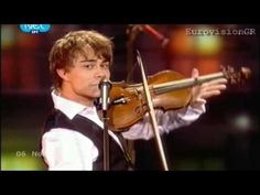 a young man holding a violin while standing in front of a microphone